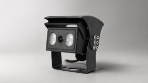 Black vehicle camera with sunshield and mounting bracket on a gray studio background