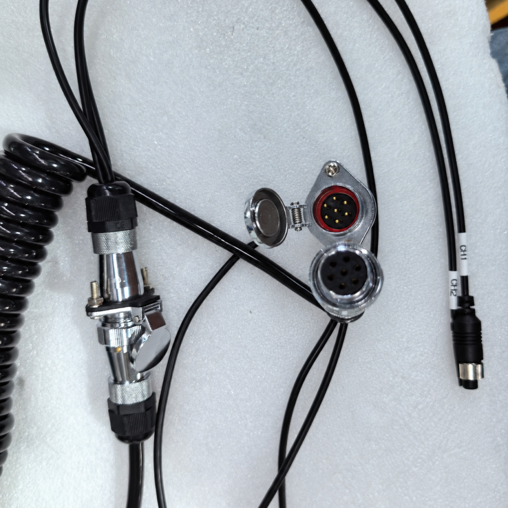 Disconnected circular connectors with visible pins and sockets, an open hinged cover, and attached cables on white foam